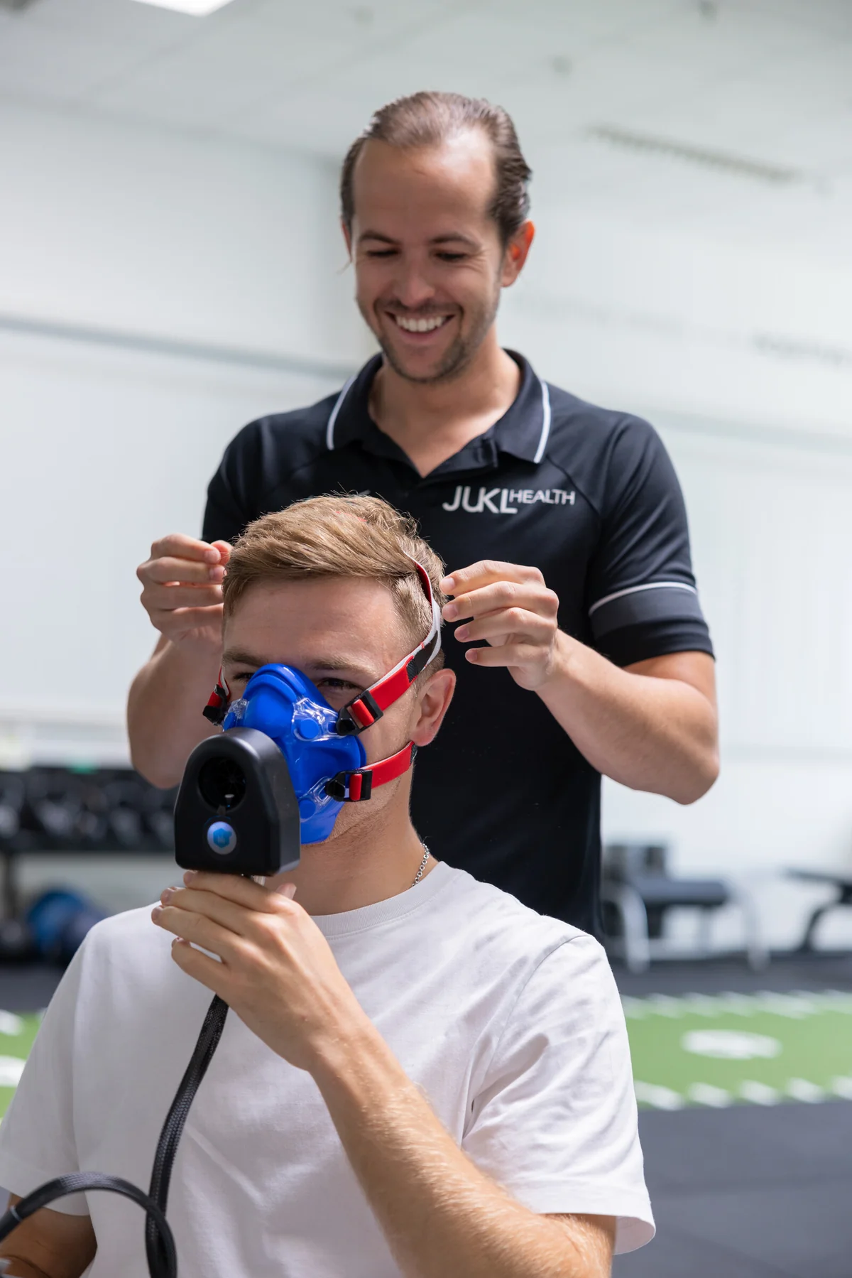 Coach legt einem Athleten die Atemmaske für die Leistungsdiagnostik an