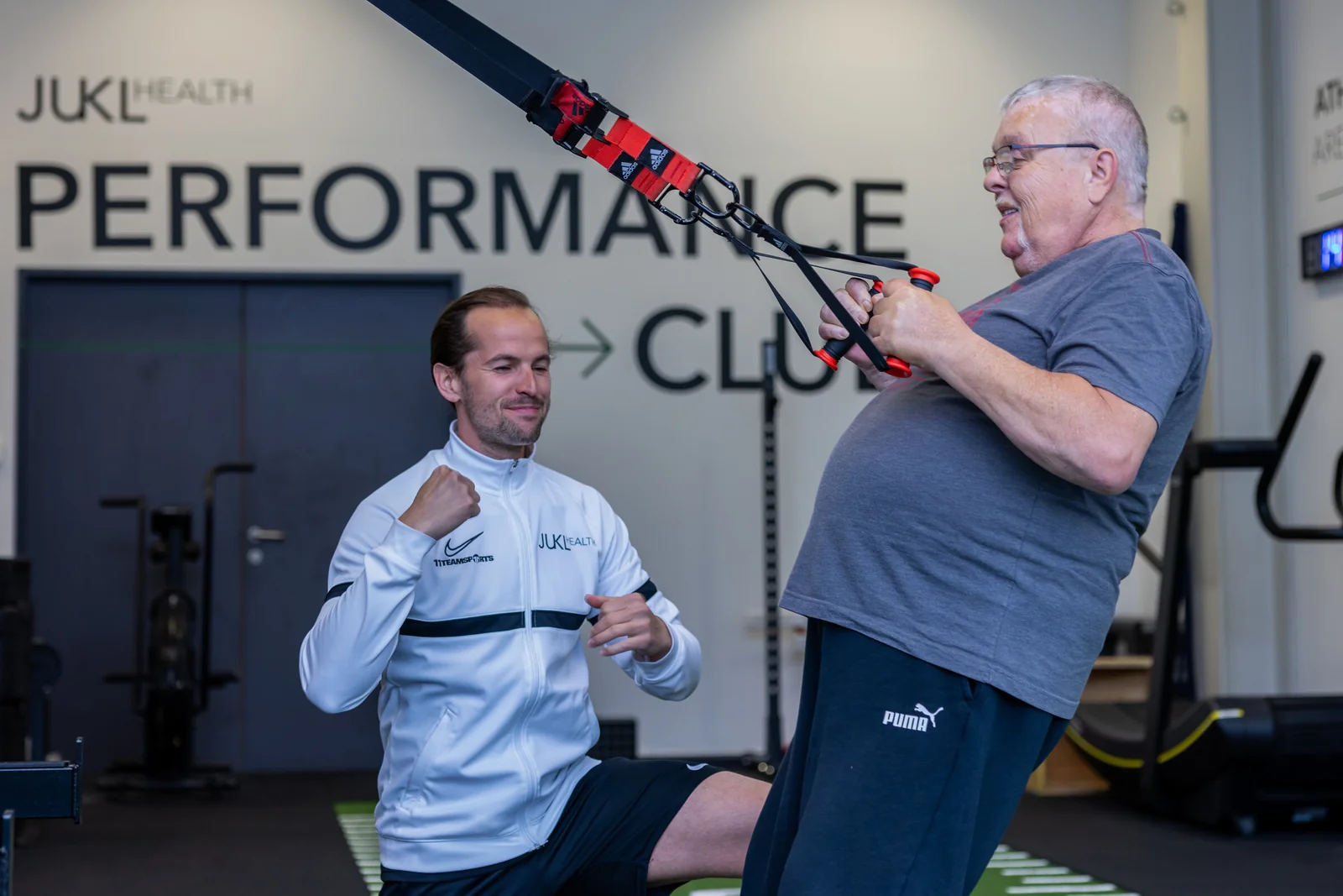 Coach trainiert mit einem Kunden am Schlingentrainer