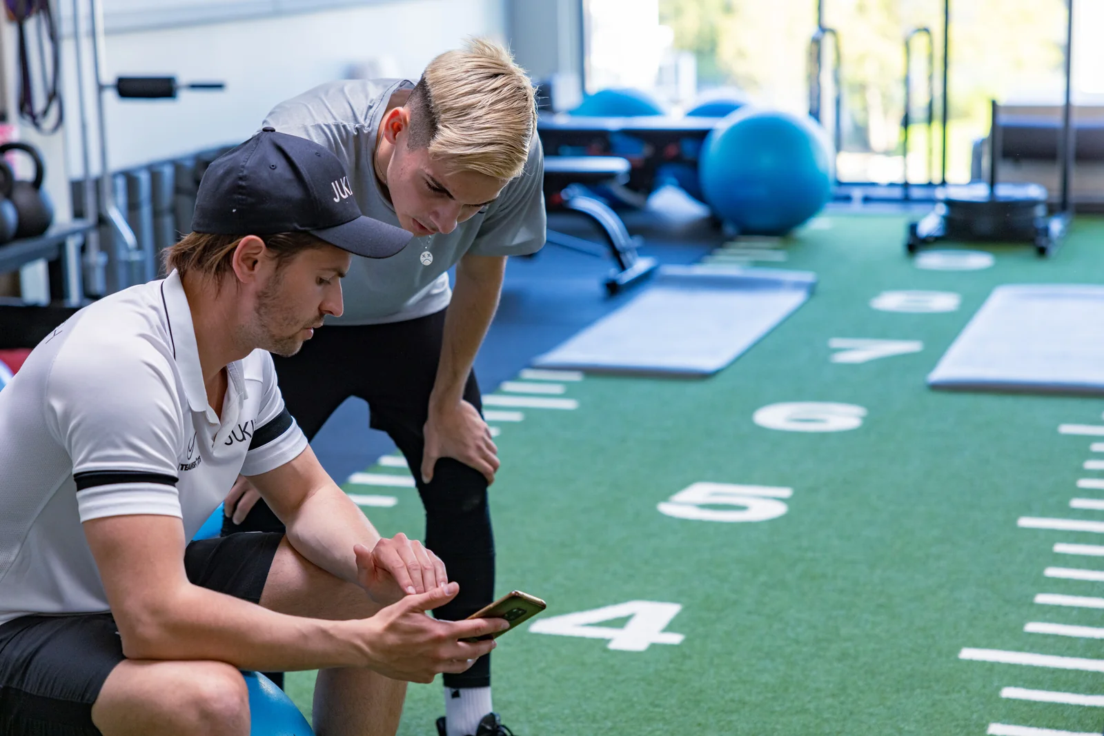 Coach und Athlet besprechen den Trainingsplan am Smartphone