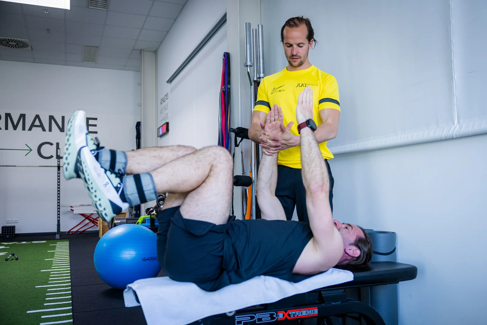 Coach begleitet einen Klienten bei einer Übung auf der Behandlungsbank