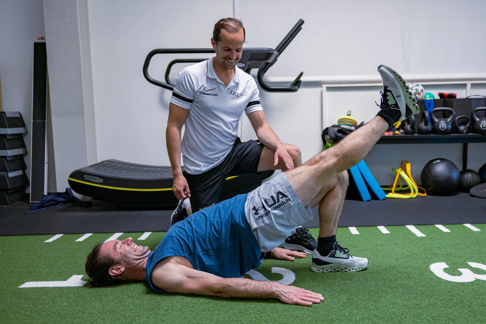 Coach korrigiert einen Klienten bei einer Übung am Boden